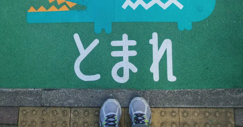 Japanese "tomare" (stop) sign painted on the ground in front of a pair of trainers