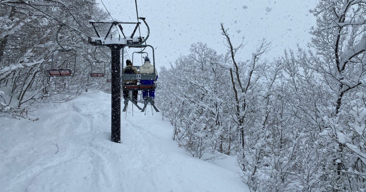 Chairlift climbing through snow-covered trees in falling snow at Okutone Ski Resort in Minakami, Gunma