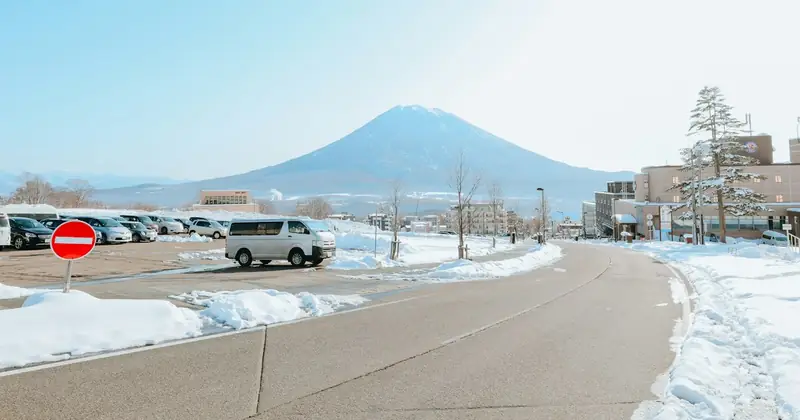 Snowy road leading towards a snow-capped volcano in winter