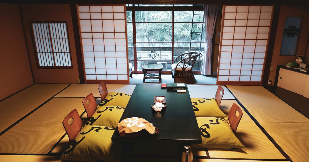 Traditional ryokan guest room at Shuzenji Onsen on the Izu Peninsula, with tatami mats, a low table set for guests and shoji screens open to the garden
