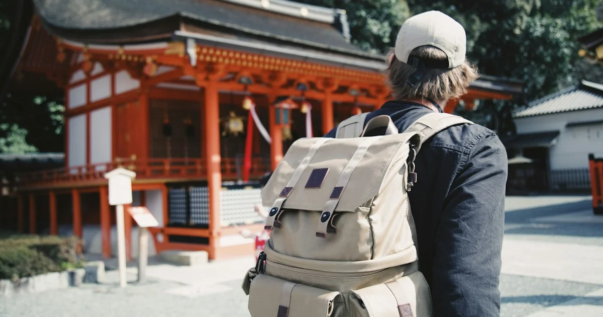 A traveller with a backpack at a red shrine in Japan